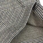 Close-up of houndstooth fabric with detailed stitching and texture, showcasing a classic pattern suitable for fashion and tailoring.