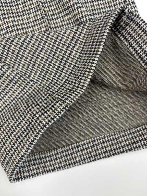 Close-up of houndstooth fabric with detailed stitching and texture, showcasing a classic pattern suitable for fashion and tailoring.