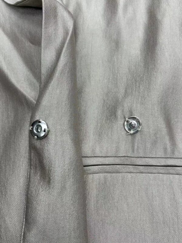 Close-up of a stylish grey blazer with silver buttons, showcasing high-quality fabric and tailored fit, perfect for formal or business occasions.