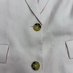 Close-up of a beige blazer featuring two large, shiny buttons and a tailored lapel, perfect for stylish professional or casual wear.