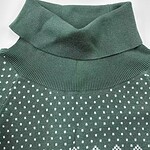 Close-up of a green turtleneck sweater with white polka dots, showcasing the ribbed collar and fabric texture.