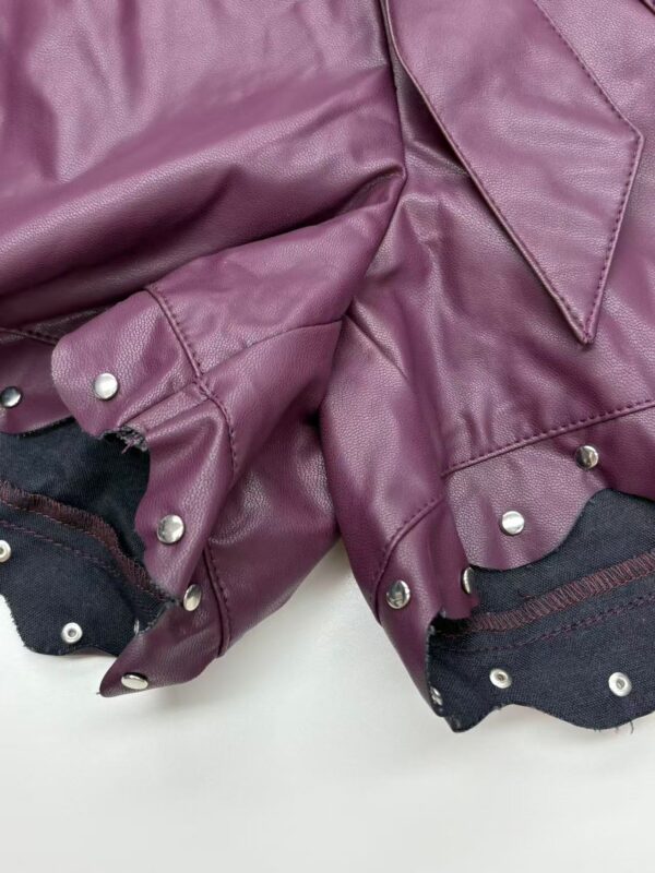 Close-up of a purple leather jacket with silver studs and black fabric lining, showcasing trendy fashion details.