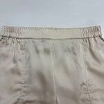 Close-up of beige satin shorts with elastic waistband, perfect for casual or lounge wear, showcasing smooth fabric and comfortable fit.