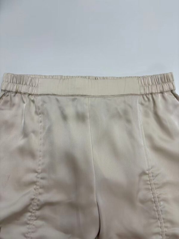 Close-up of beige satin shorts with elastic waistband, perfect for casual or lounge wear, showcasing smooth fabric and comfortable fit.