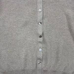 Close-up of a grey women's cardigan with button closure, showcasing soft knit fabric and classic design, perfect for casual or office wear.