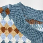 Close-up of a cozy argyle sweater featuring blue, brown, white, and beige diamond patterns with a ribbed neckline.
