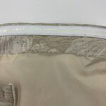 Detailed close-up of beige fabric with a visible zipper and stitching, highlighting the texture and quality of the material.