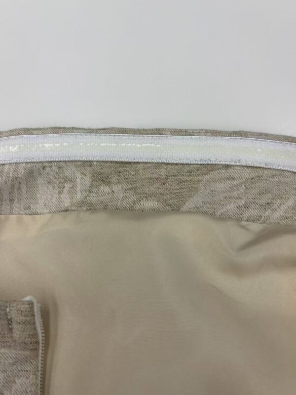 Detailed close-up of beige fabric with a visible zipper and stitching, highlighting the texture and quality of the material.
