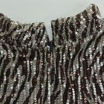 Close-up of a sequin dress with black and silver sequins, showcasing a high neckline and intricate design for stylish evening wear.