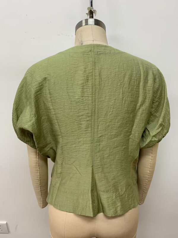 Front view of a stylish green textured blouse with puffed sleeves, displayed on a mannequin, perfect for casual or formal wear.