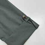 Close-up of stylish green women's trousers with gold button detail and tailored fit, perfect for office or casual wear.