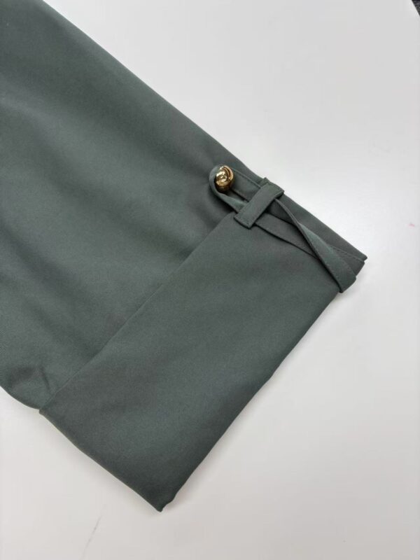 Close-up of stylish green women's trousers with gold button detail and tailored fit, perfect for office or casual wear.