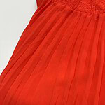 Close-up of a bright red pleated skirt with a high elastic waistband, showcasing fine pleats and smooth fabric texture, perfect for fashion and style.