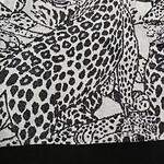 Close-up of a stylish women's sweater with a bold leopard print pattern in black and white, featuring a round neckline and ribbed hem.