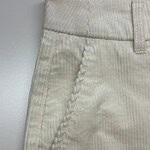 Close-up of cream-colored corduroy pants showing textured fabric and detailed stitching on the pocket area.