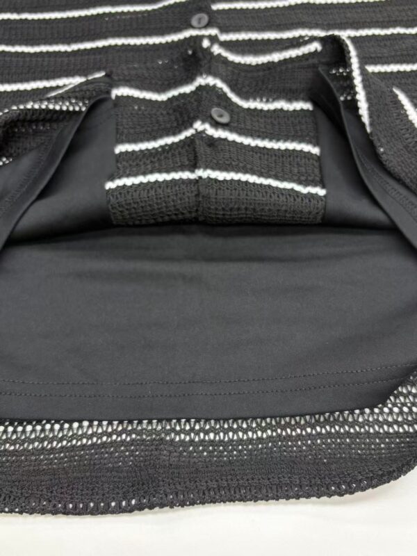 Close-up of a stylish black and white striped jacket with zipper details, perfect for casual or formal wear.