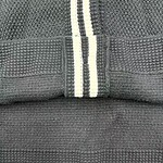 Detailed close-up of black knit fabric with textured patterns and white stripe detail, showcasing quality material and craftsmanship.