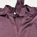 Close-up of a mauve satin blouse with a bow tie collar, showcasing luxurious fabric and stylish design, perfect for fashionable women's wear.