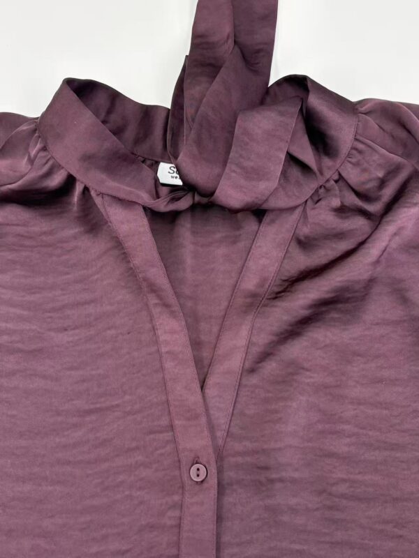 Close-up of a mauve satin blouse with a bow tie collar, showcasing luxurious fabric and stylish design, perfect for fashionable women's wear.