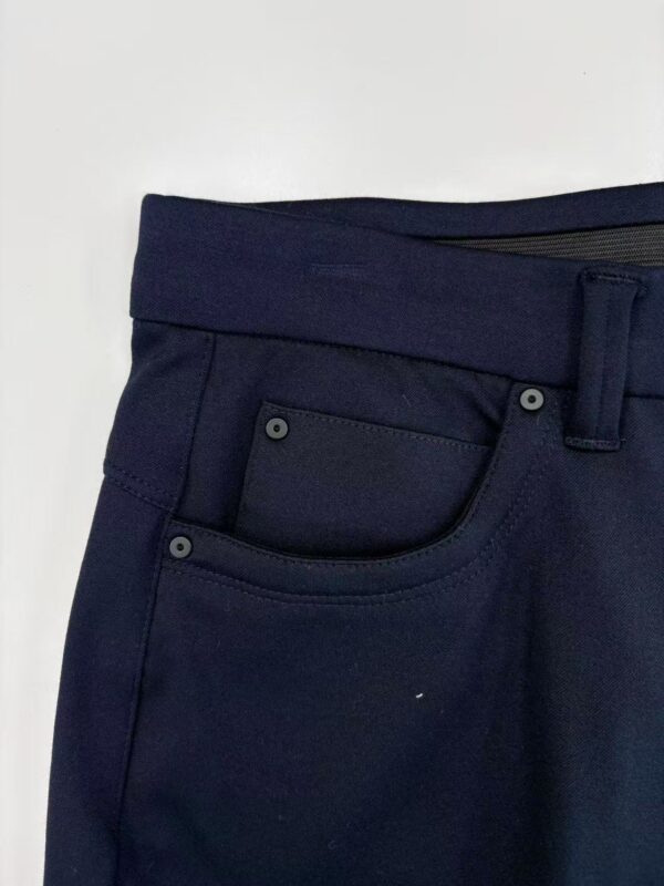 Close-up of navy blue men's dress pants showing waistband, belt loop, and front pocket details, perfect for formal or business attire.