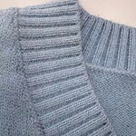 Close-up of a light gray knitted sweater with ribbed collar and textured pattern, perfect for casual or formal wear.
