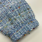 Close-up of vibrant multicolored tweed fabric with textured weave, ideal for high-end fashion and clothing accessories.