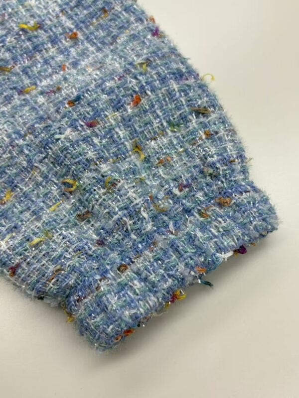 Close-up of vibrant multicolored tweed fabric with textured weave, ideal for high-end fashion and clothing accessories.