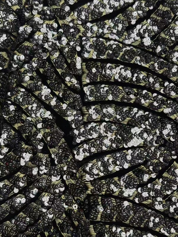 Close-up of black fabric adorned with shiny silver sequins, perfect for glamorous clothing and accessories.