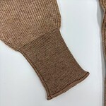 Close-up of a brown knit sweater sleeve showing detailed ribbed cuff and textured fabric, perfect for fall and winter fashion.