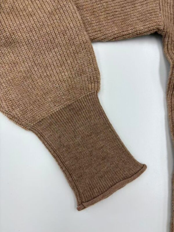 Close-up of a brown knit sweater sleeve showing detailed ribbed cuff and textured fabric, perfect for fall and winter fashion.