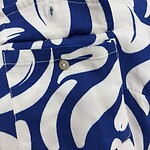 Close-up of a stylish shirt with a bold blue and white leaf pattern, featuring a buttoned pocket and collar detail, perfect for fashion-forward outfits.