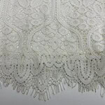 Close-up of intricate white lace fabric with floral and geometric patterns, perfect for fashion and bridal wear.