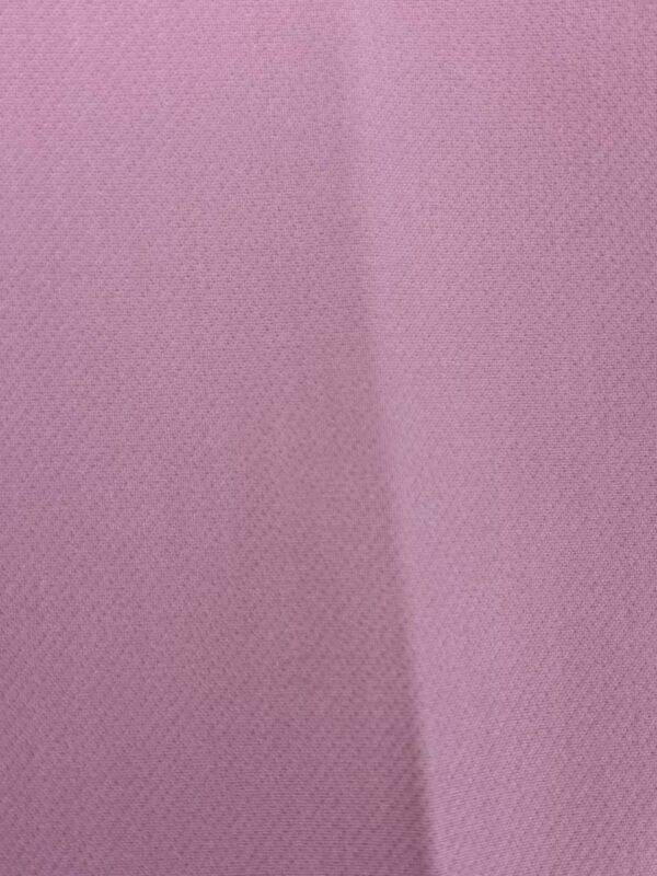 Close-up of pink mesh fabric with small perforations, ideal for fashion and clothing design projects.