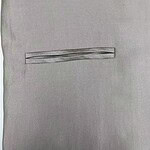Close-up of light gray suit fabric with a horizontal pocket detail, showcasing fine texture and craftsmanship.