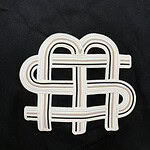 Close-up of a black sweater featuring a distinctive embroidered logo design in white and beige tones.