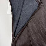 Close-up of a brown leather jacket with a gray wool lining, showcasing quality craftsmanship and fashionable design.