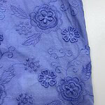 Close-up of blue fabric with intricate floral embroidery, showcasing detailed stitching and textured design, ideal for fashion or home decor.