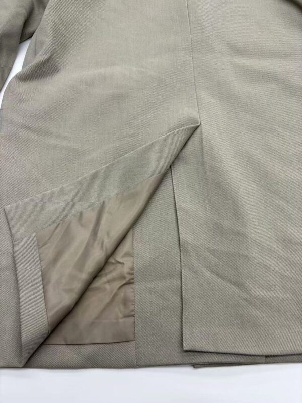 Close-up of a beige women's skirt showing fabric texture and slit detail, perfect for fashion and style enthusiasts.