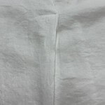 Detailed close-up of a white fabric seam, showcasing fine stitching and smooth texture, ideal for fashion and textile product descriptions.