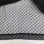 Close-up of black and white polka dot fabric with textured pattern, ideal for fashion and clothing design.