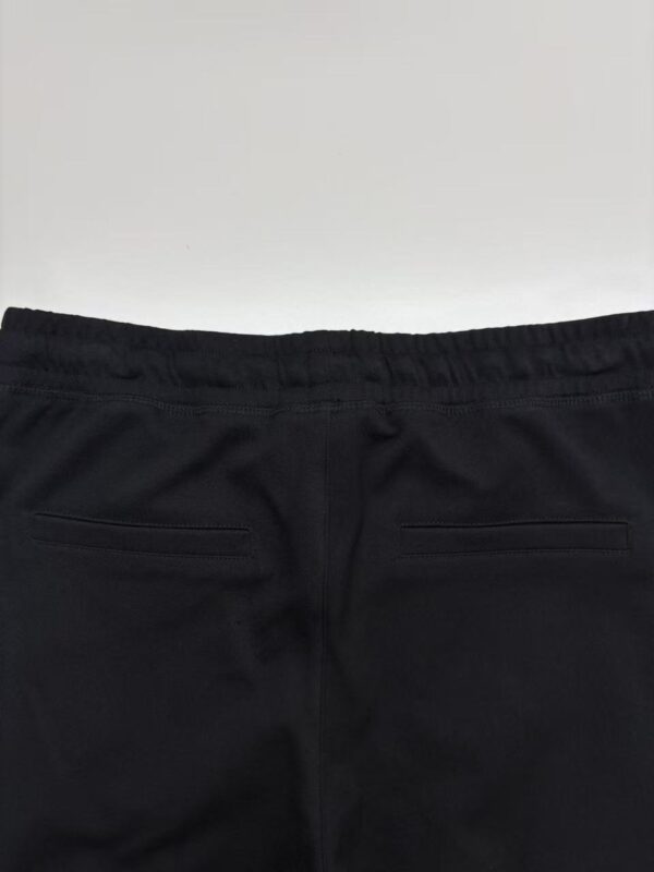 Close-up of black casual pants with elastic waistband and rear pockets, suitable for everyday wear and fashion.