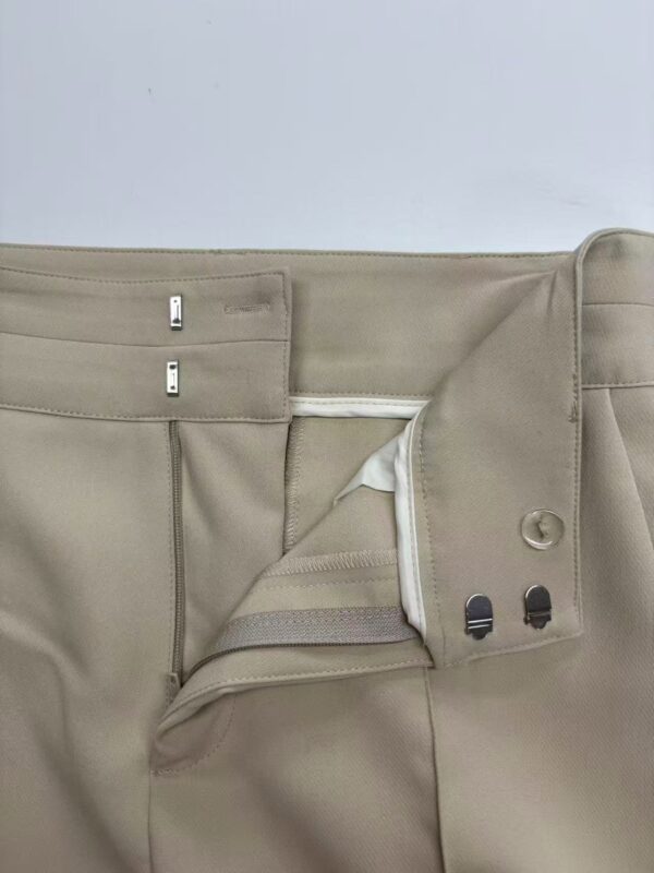 Close-up of beige men's formal trousers showing zipper, button, and waistband details, suitable for office wear and professional attire.