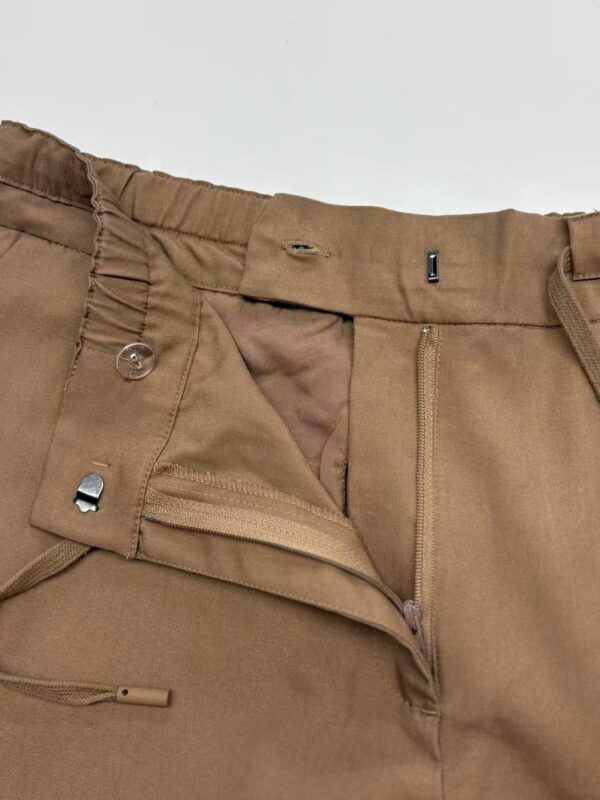 Close-up of men's khaki pants showing zipper, button, and waistband details, suitable for casual or semi-formal wear.