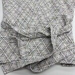Close-up of a stylish women's tweed blazer with a classic checkered pattern, perfect for professional or casual wear.