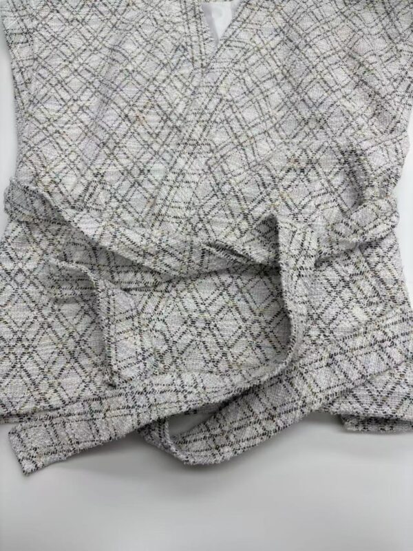 Close-up of a stylish women's tweed blazer with a classic checkered pattern, perfect for professional or casual wear.