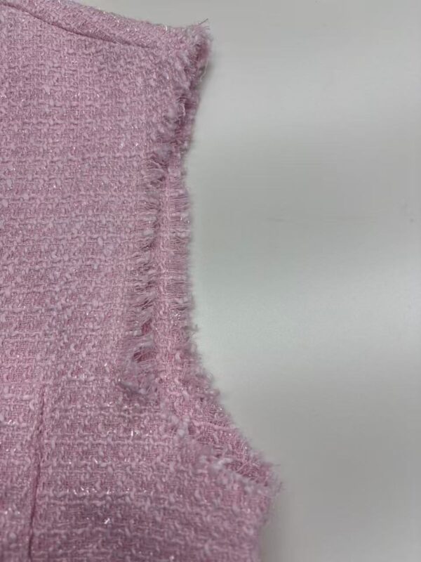 Close-up of pink textured fabric with frayed edge, showcasing detailed weave and soft appearance.