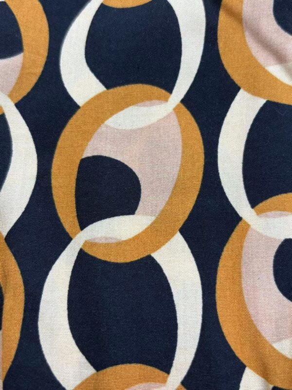 Close-up of fabric with a colorful chain link pattern featuring navy, white, beige, and mustard yellow links, ideal for fashion and textile design.