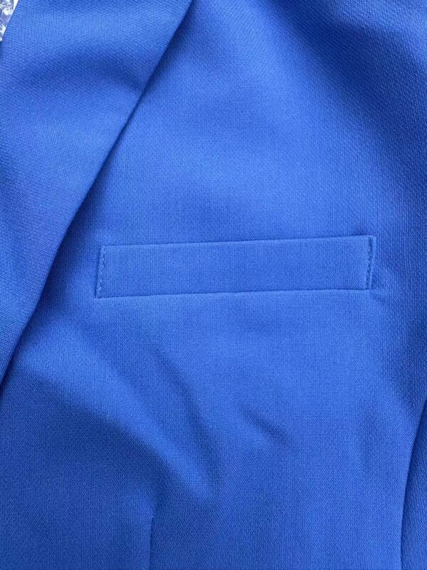 Close-up of a vibrant blue suit fabric with a welt pocket, showcasing fine texture and quality tailoring for men's fashion.