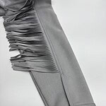 Close-up of a grey dress with fringe detailing on the sleeve, showcasing stylish and modern fashion design.