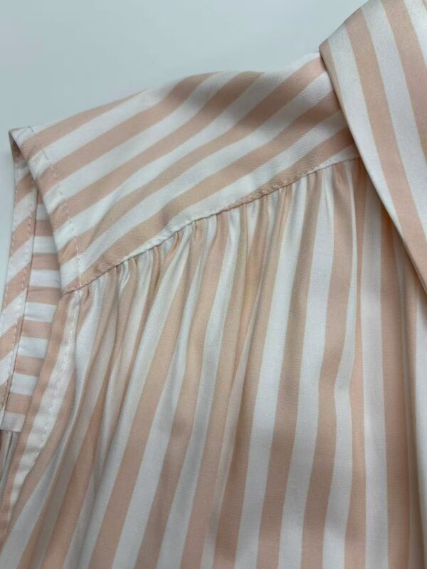 Close-up of a stylish beige and white striped blouse with pleated details, perfect for casual or office wear.